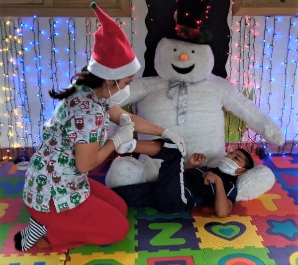 Physiotherapist helping young boy with big toy snowman in background