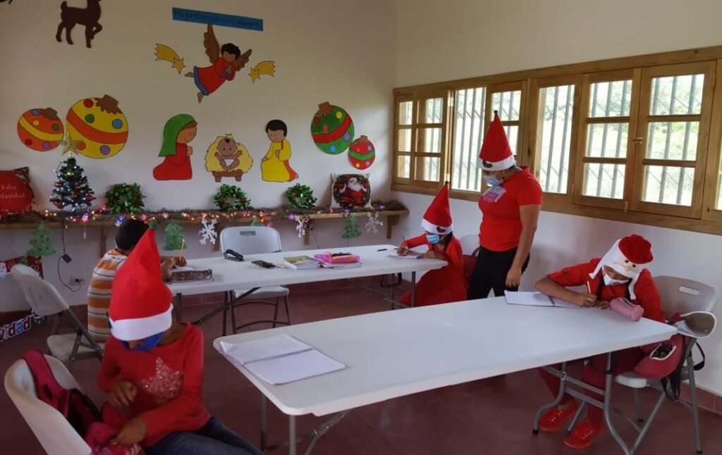 Tutor helping students, all wearing Santa hats