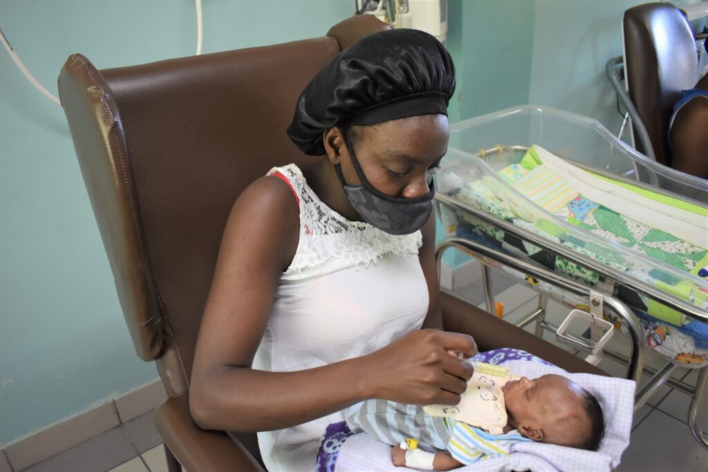 A mother feeding her newborn baby with a syringe on a neonatal ward